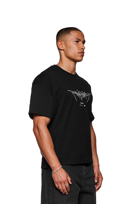 Mann trägt Isolation T-Shirt Regular Black mit Siebdruck „Isolation“-Grafik und silbernem Armband, unisex, reguläre Passform.