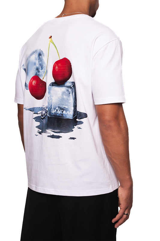 Person trägt NC Tee White Regular mit „Neighbour's Cherries“-Grafik auf Rückseite und gesticktem OLAKALA Logo auf Brust; unisex, reguläre Passform.