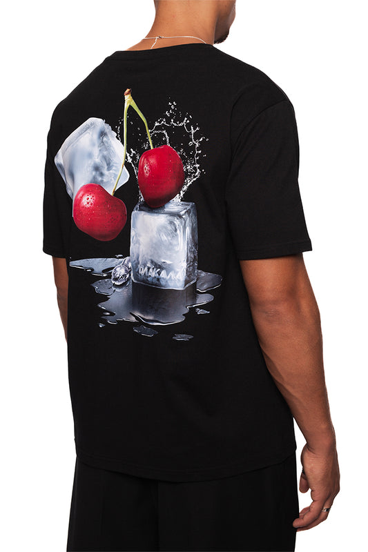 Mann trägt das NC Tee Black Regular mit gesticktem OLAKALA Logo und „Neighbour's Cherries“-Grafikdruck auf dem Rücken. Unisex, reguläre Passform.